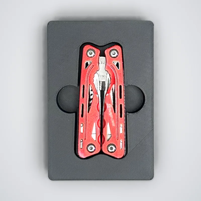 A multitool in its shadowbox, with a finger hole on each side